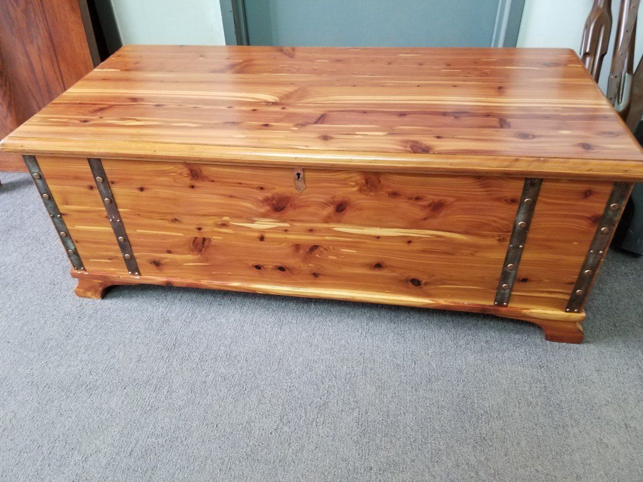 Wooden storage chest with metal straps on a carpeted floor