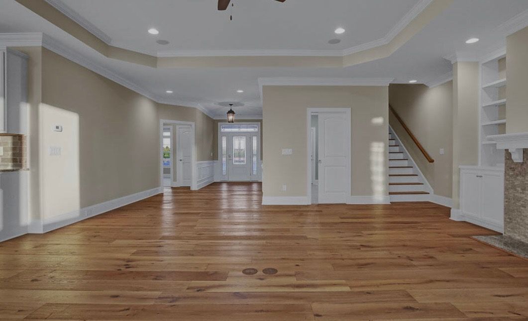 An empty living room with hardwood floors and stairs.
