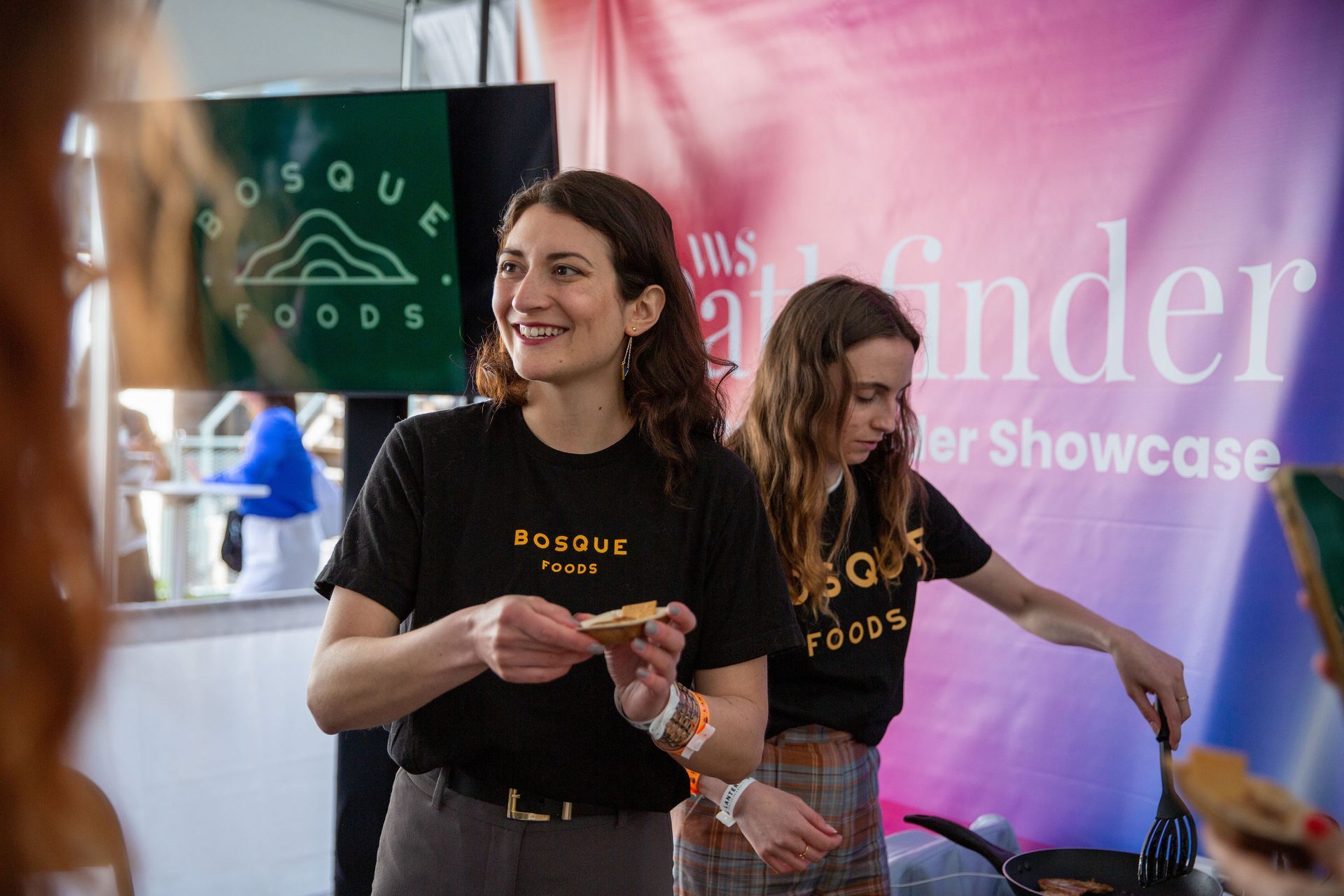 Two women are standing next to each other at a food festival.