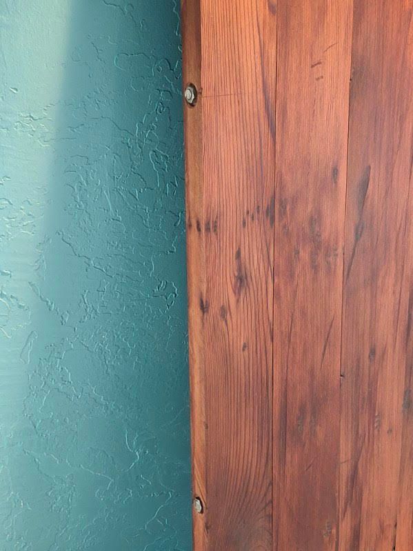 Close-up of a wooden door edge beside a teal textured wall.