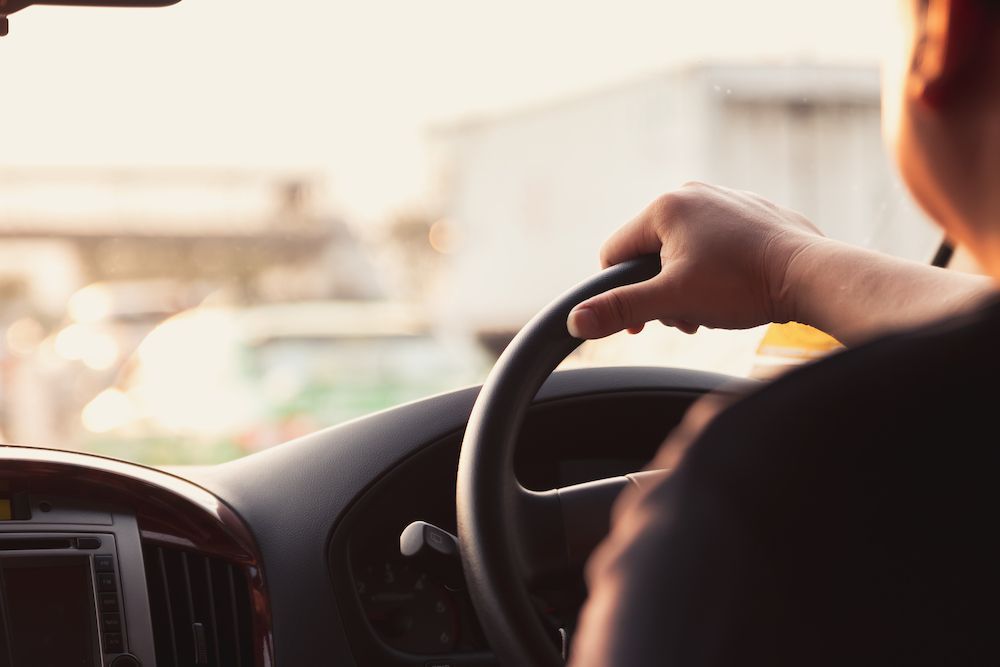 A Man is Driving a Car With His Hand on the Steering Wheel — Crakka Windscreens in Nabiac, NSW