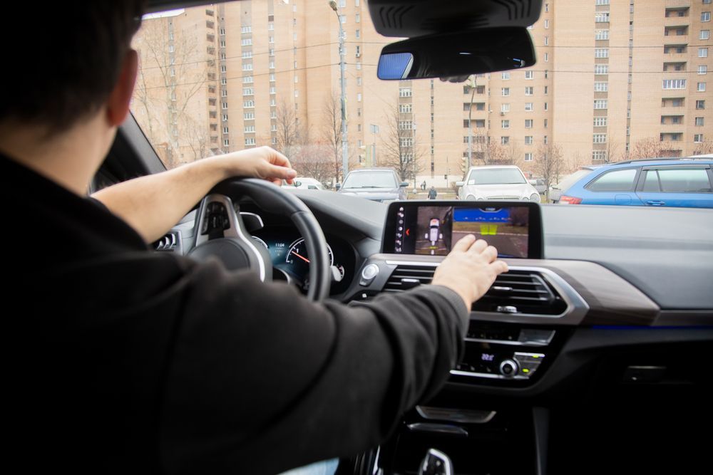 A man is driving a car and looking at the car camera — Crakka Windscreens in Diamond Beach, NSW