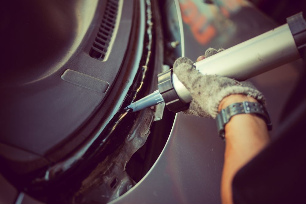 A Person is Applying Sealant to a Car Door — Crakka Windscreens in Old Bar, NSW
