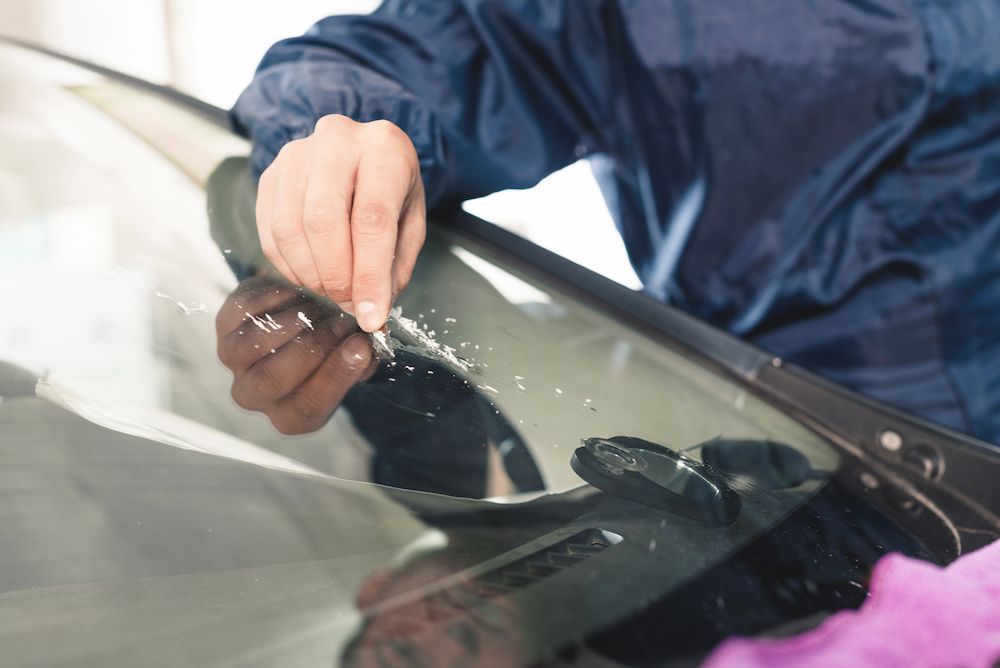 A Man is Fixing a Broken Windshield on a Car — Crakka Windscreens in Forster-Tuncurry, NSW