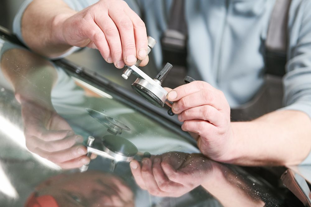 A Man is Fixing a Broken Windshield on a Car — Crakka Windscreens in Nabiac, NSW