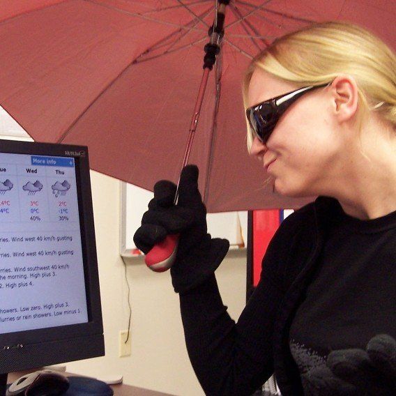 Woman holding umbrella looking at computer