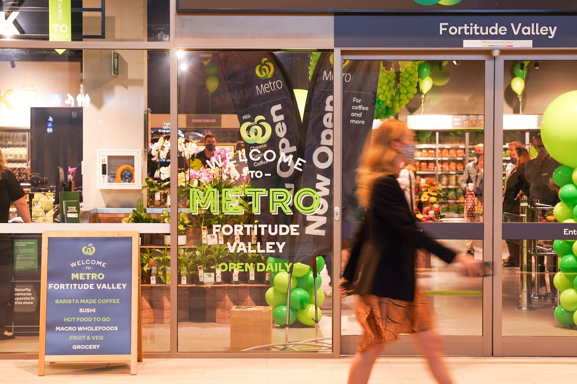 A woman is walking in front of a metro store.