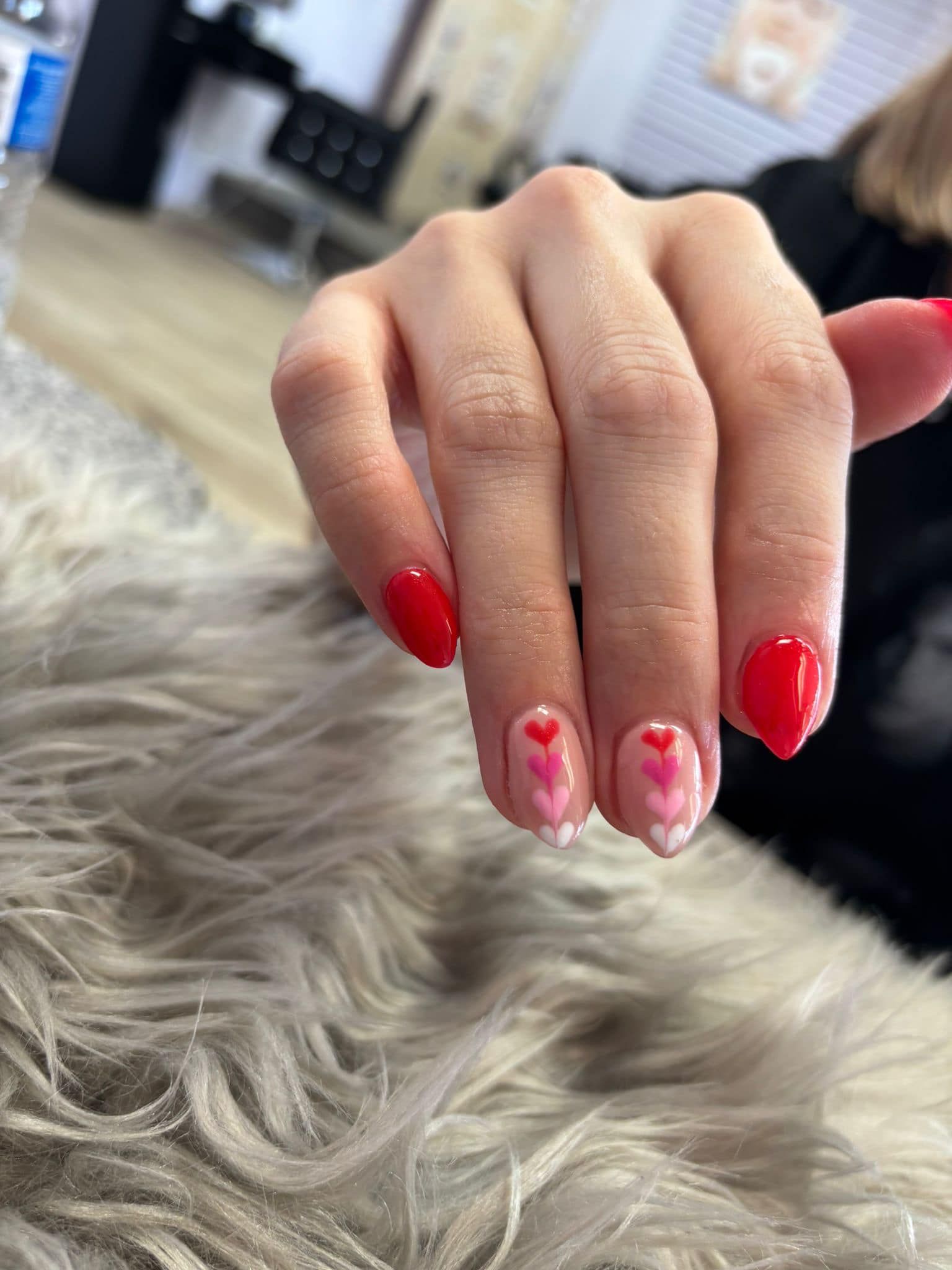 A close up of a woman 's hand with red nails and hearts on them.