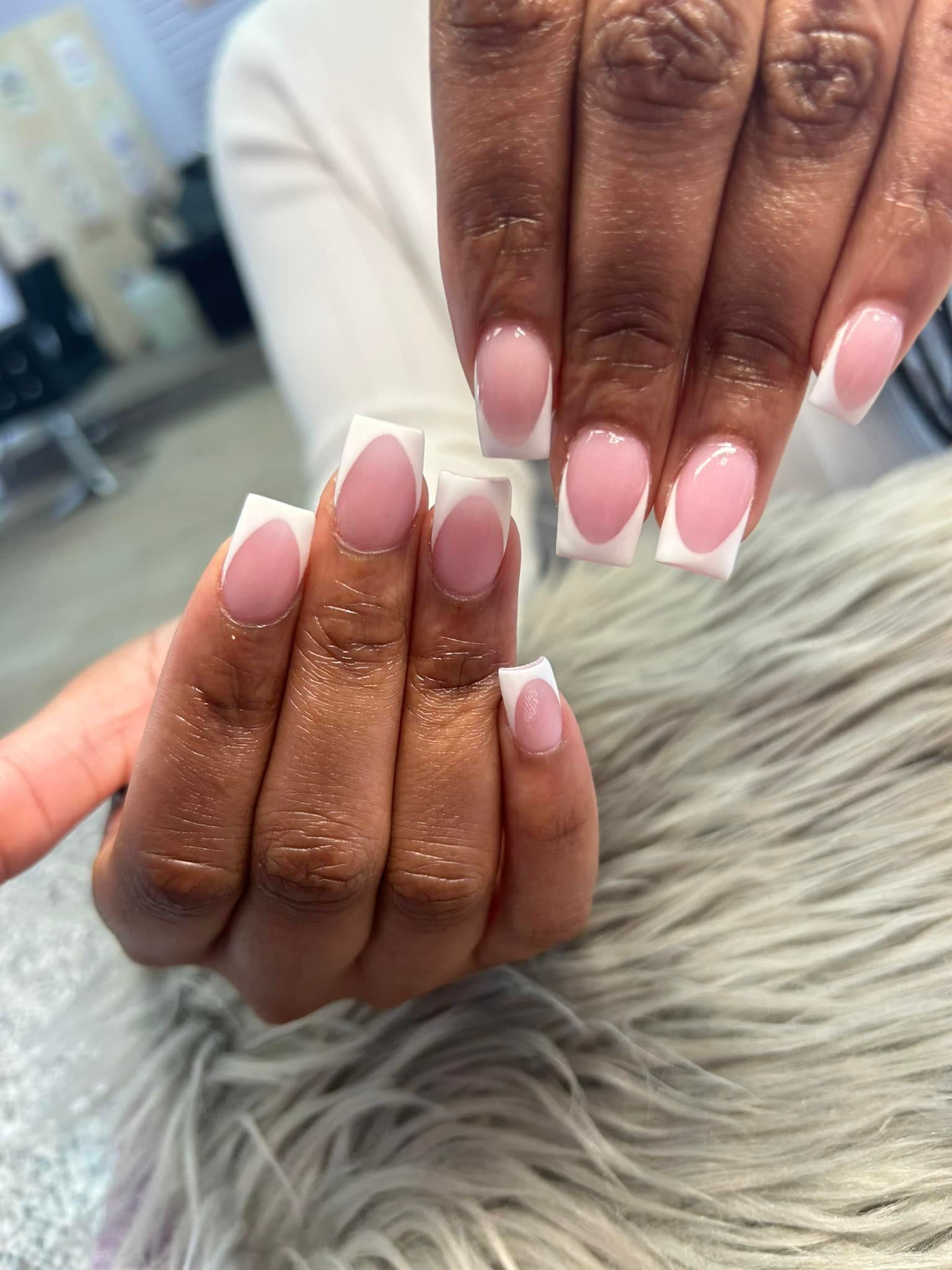 A close up of a woman 's nails with pink and white french manicure.