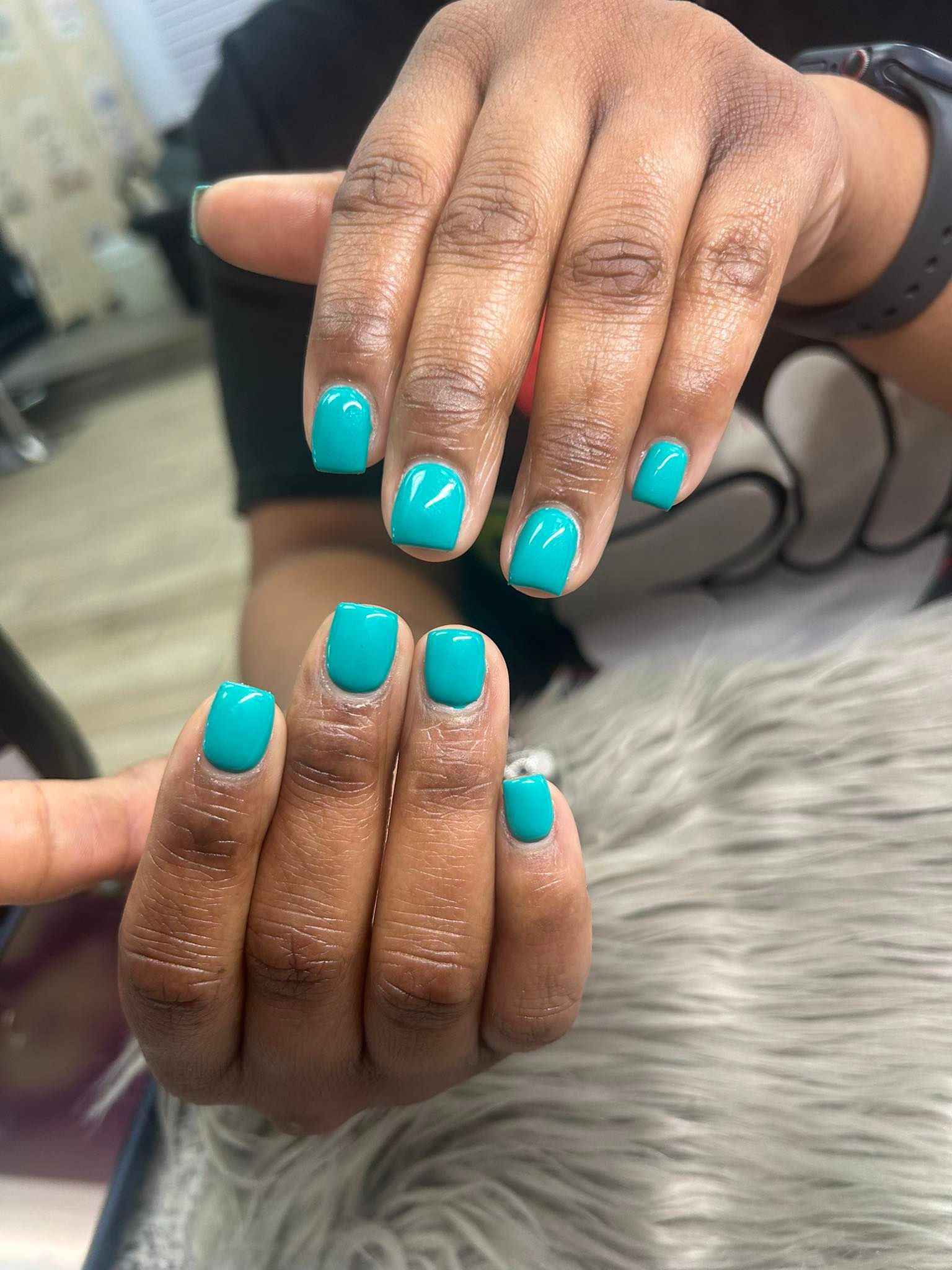 A close up of a woman 's hands with blue nails.