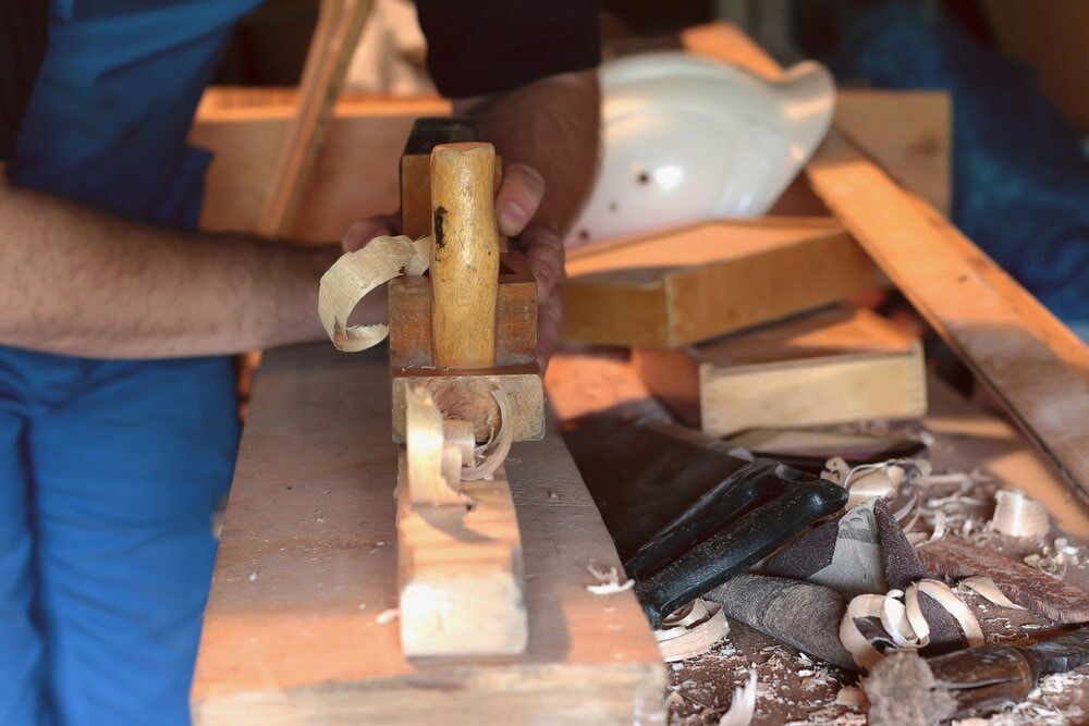 A Man Is Using A Plane To Carve A Piece Of Wood — ASM Joinery In Fyshwick, ACT