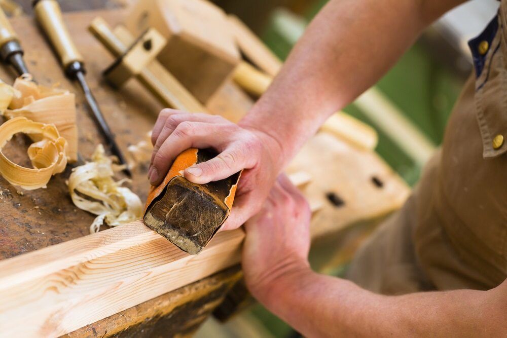 A Man Is Using A Sander To Sand A Piece Of Wood — ASM Joinery In Fyshwick, ACT