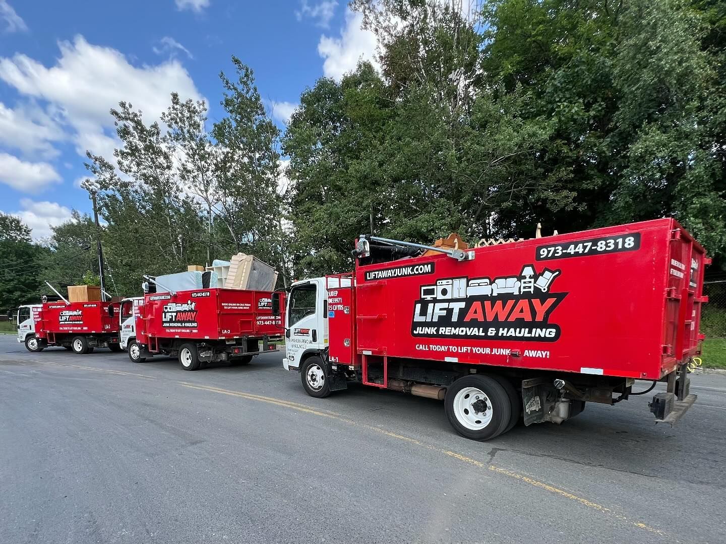 Three red Lift Away junk removal trucks parked on a paved surface.