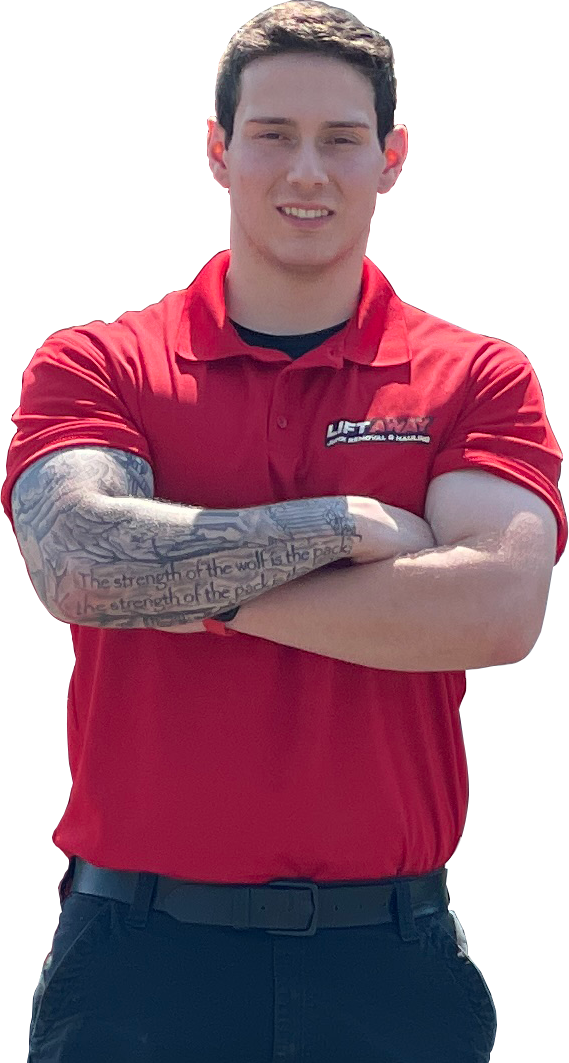 Man with arms crossed, wearing a red polo and dark pants, with tattoos on his arm, smiling.