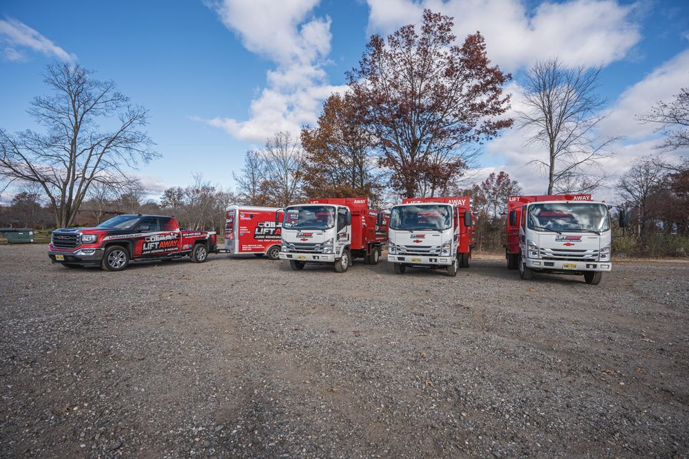 A line of red and white service vehicles parked on gravel under a blue sky.