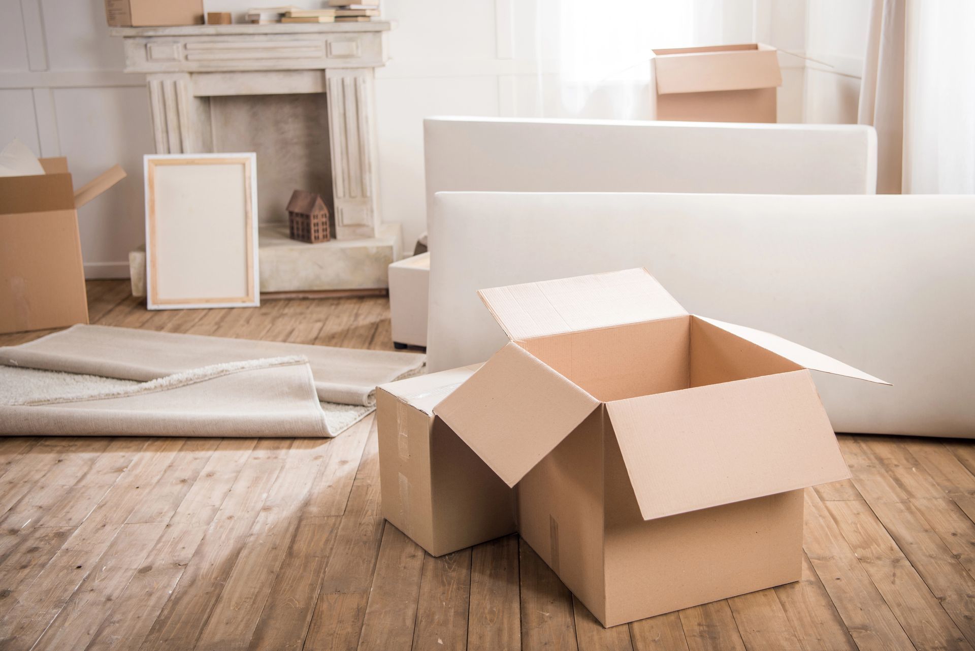 Boxes in a room being packed for a move, with furniture and an empty fireplace.