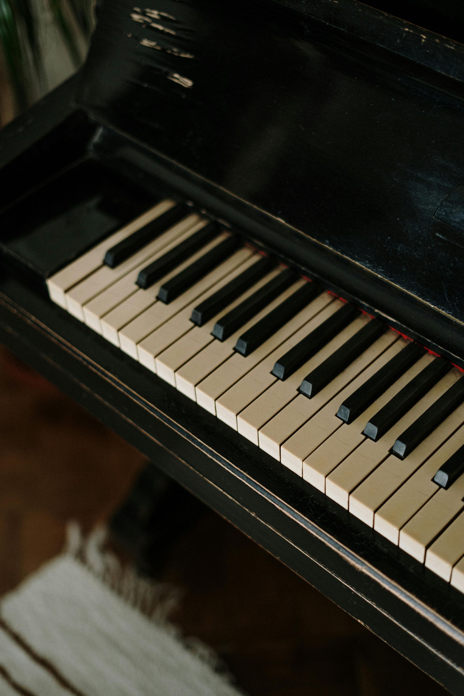 Close-up of a black piano keyboard, ivory keys, with worn, black paint.