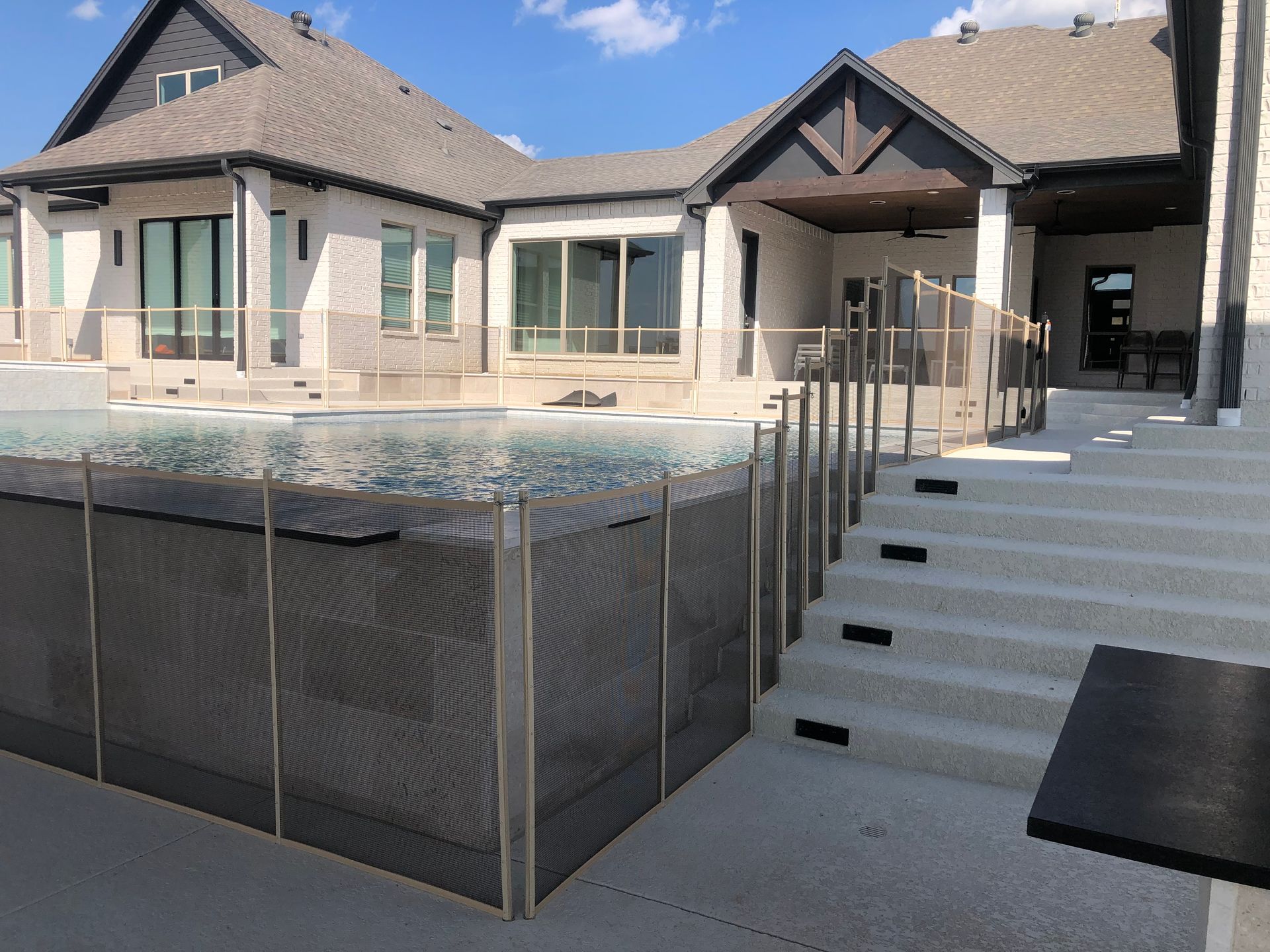 Backyard patio with a covered pool, stone steps, and a single-story house in the background