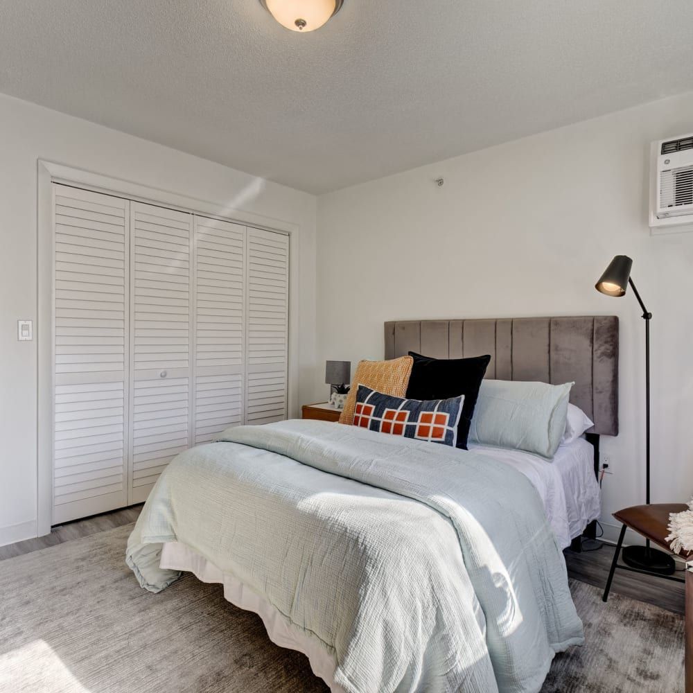 A bedroom with a large bed , a lamp , and a closet.