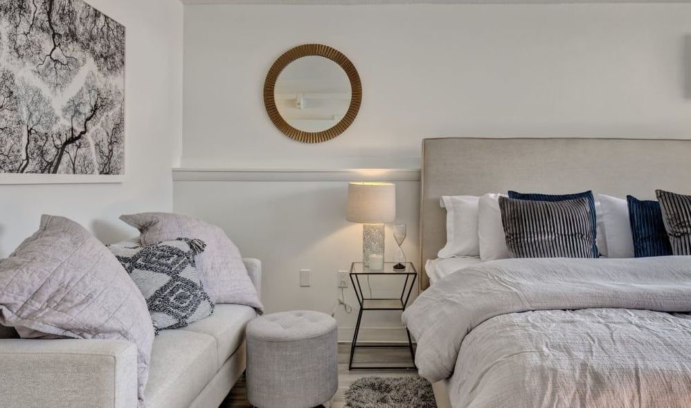 A bedroom with a bed , couch , and mirror.
