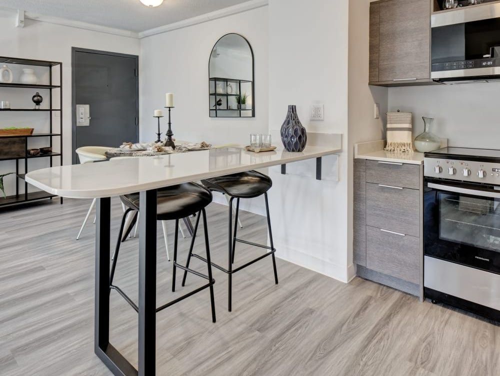 A kitchen with a table and stools and a stove.