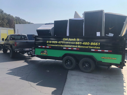 A truck towing a trailer loaded with junk, a sign reads 
