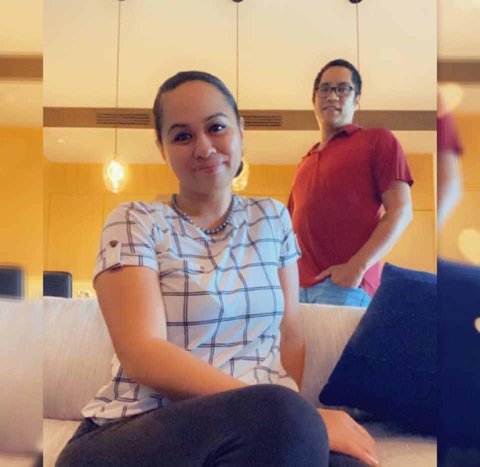 A woman is sitting on a couch with a man standing behind her