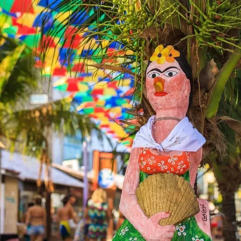 Uma estátua de frida kahlo está ao lado de uma palmeira