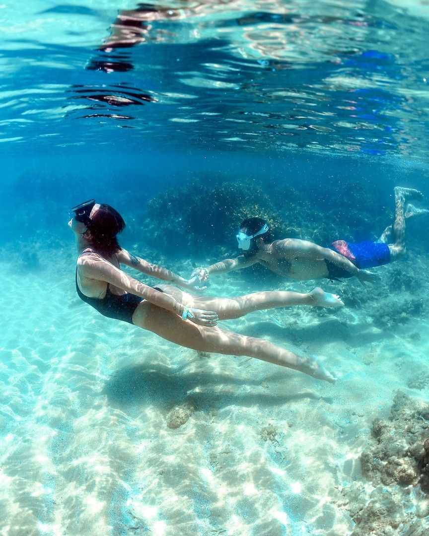 Um homem e uma mulher estão nadando debaixo d'água no oceano.