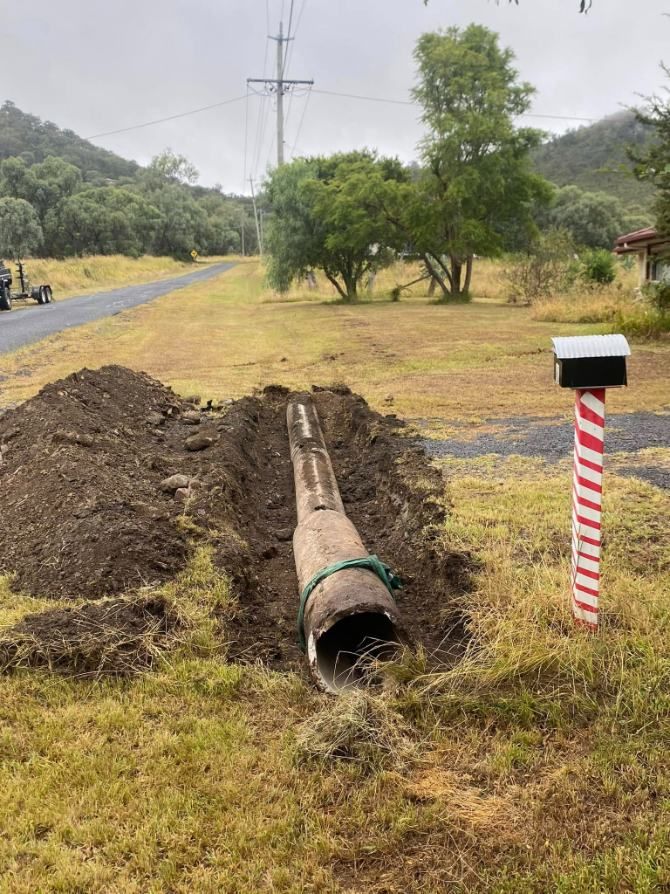 A Large Pipe is Laying in the Dirt Next to a Mailbox — Ape Earthmoving In Westbrook, QLD