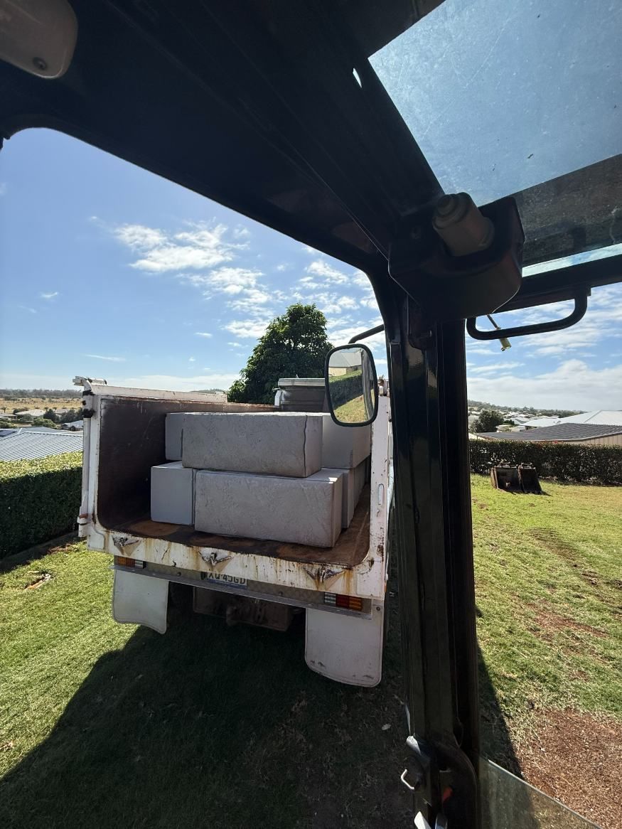 A Truck With a Stack of Bricks in the Back is Parked in a Field — Ape Earthmoving In Highfields, QLD