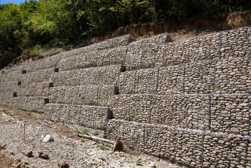 A Large Stone Wall is Sitting on Top of a Hill Next to a River — Ape Earthmoving In Gatton, QLD