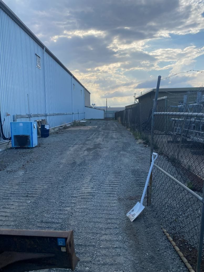 A Shovel is Sitting on the Side of a Dirt Road Next to a Chain Link Fence — Ape Earthmoving In Westbrook, QLD