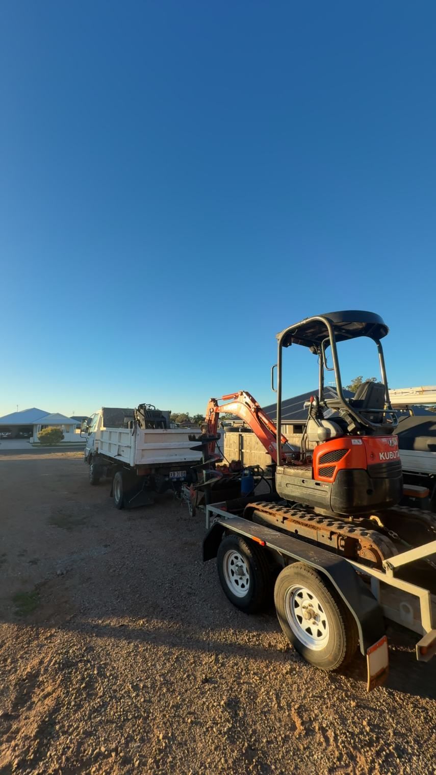 A Small Excavator is Parked on a Trailer Next to a Dump Truck — Ape Earthmoving In Westbrook, QLD