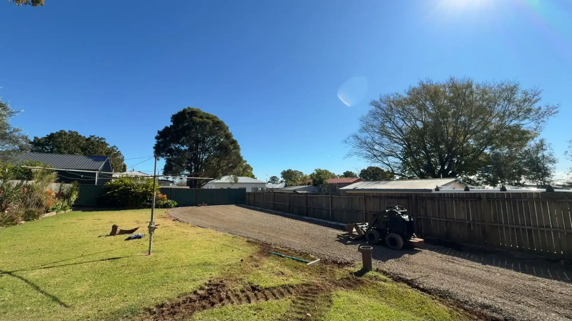 A Small Red Excavator is Parked on the Side of a Brick Building — Ape Earthmoving In Westbrook, QLD