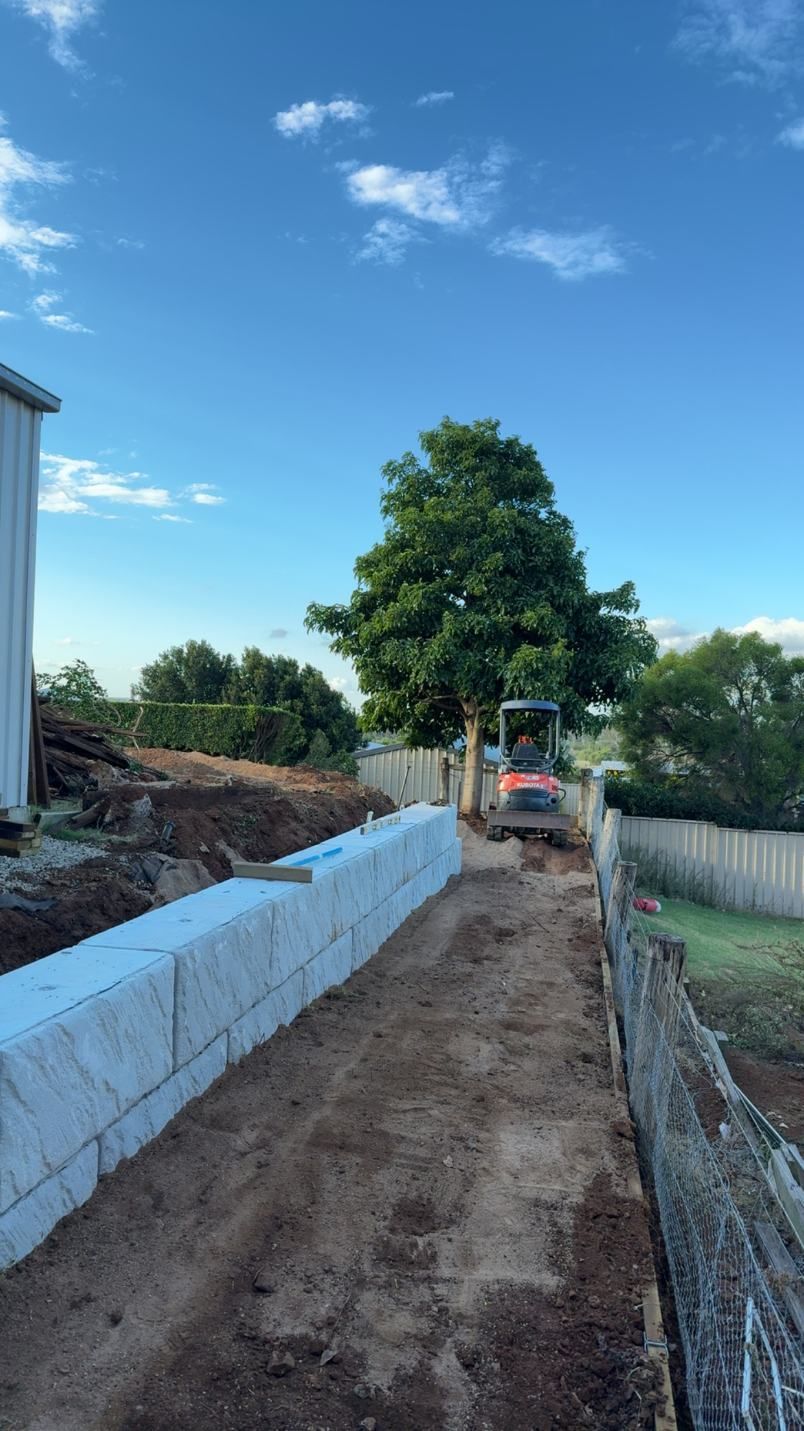 A Bulldozer is Driving Down a Dirt Road Next to a Fence — Ape Earthmoving In Warwick, QLD