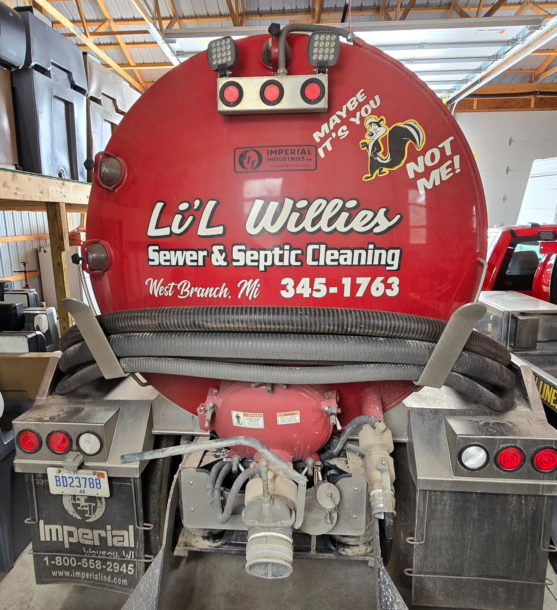 A yellow vacuum truck is parked on the side of the road in front of a building.
