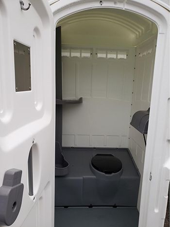 The inside of a portable toilet with the door open