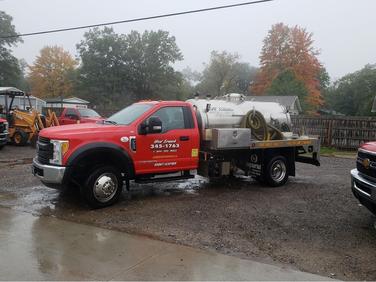 A red truck with a tank on the back is parked in a parking lot.