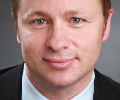 A man in a suit and tie is smiling for the camera.