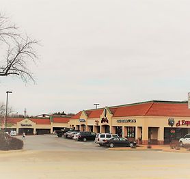 A row of stores with cars parked in front of them.
