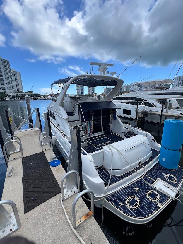 A white boat is docked at a dock in a marina.