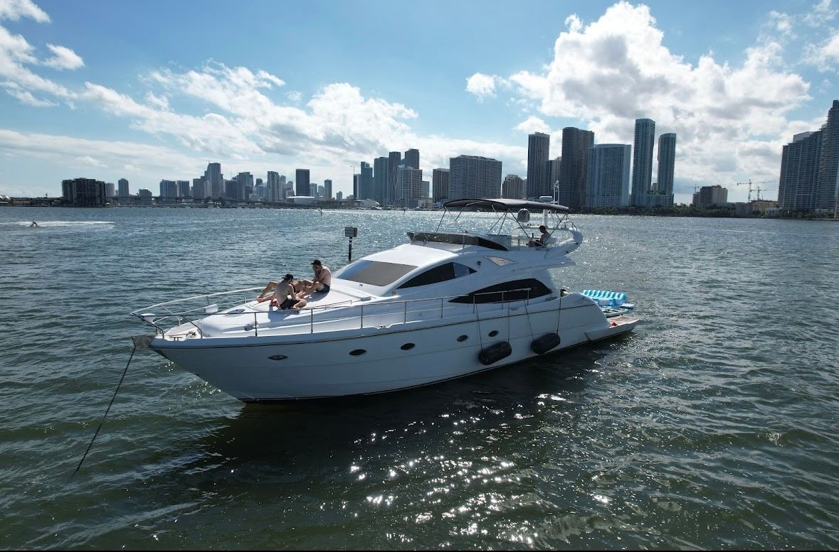 A yacht is floating on top of a body of water with a city skyline in the background.