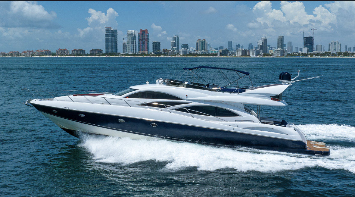 A yacht is floating on top of a body of water with a city skyline in the background.