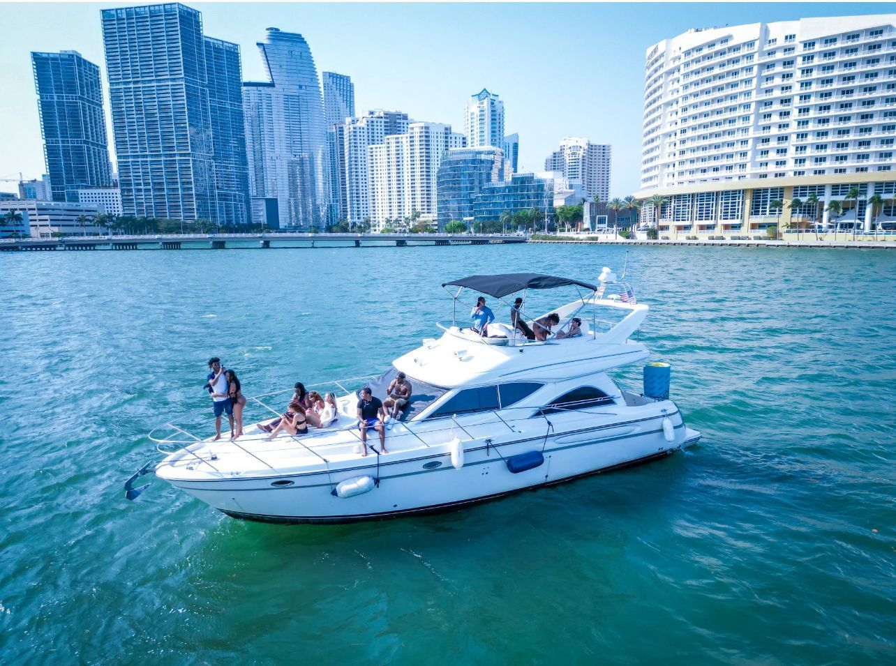 A group of people are sitting on top of a white yacht in the water.