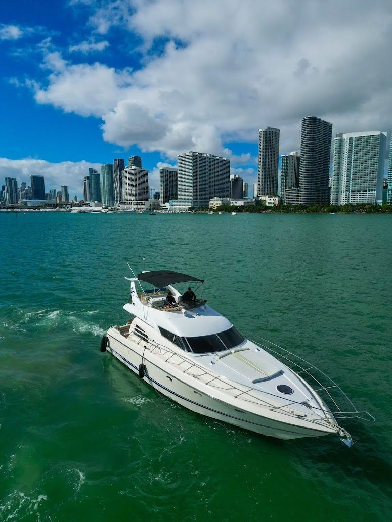 A white yacht is floating on top of a body of water with a city in the background.
