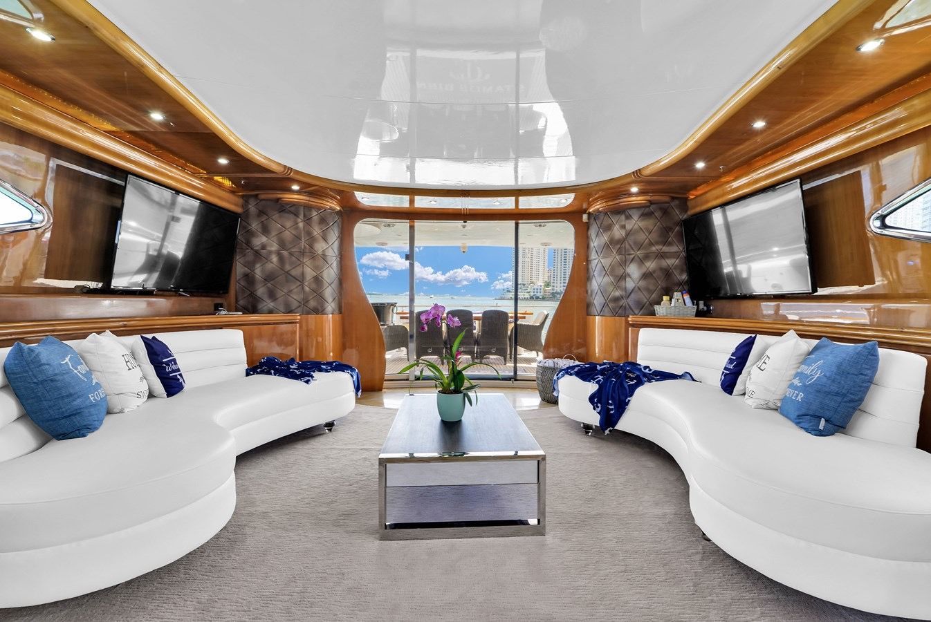 A living room on a boat with white couches and a coffee table.