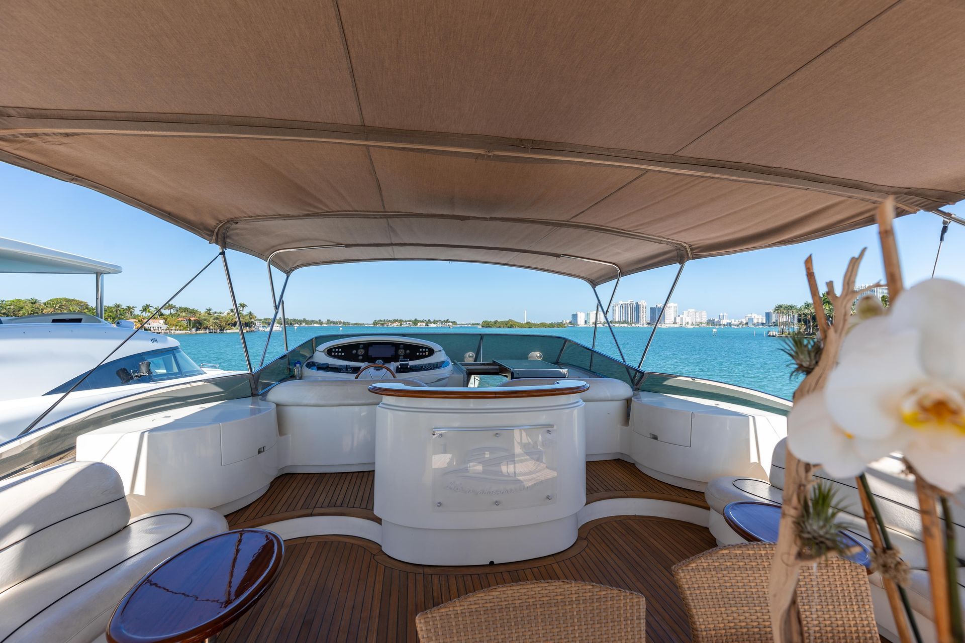 Yacht deck with helm, seating, and a view of the water and skyline.