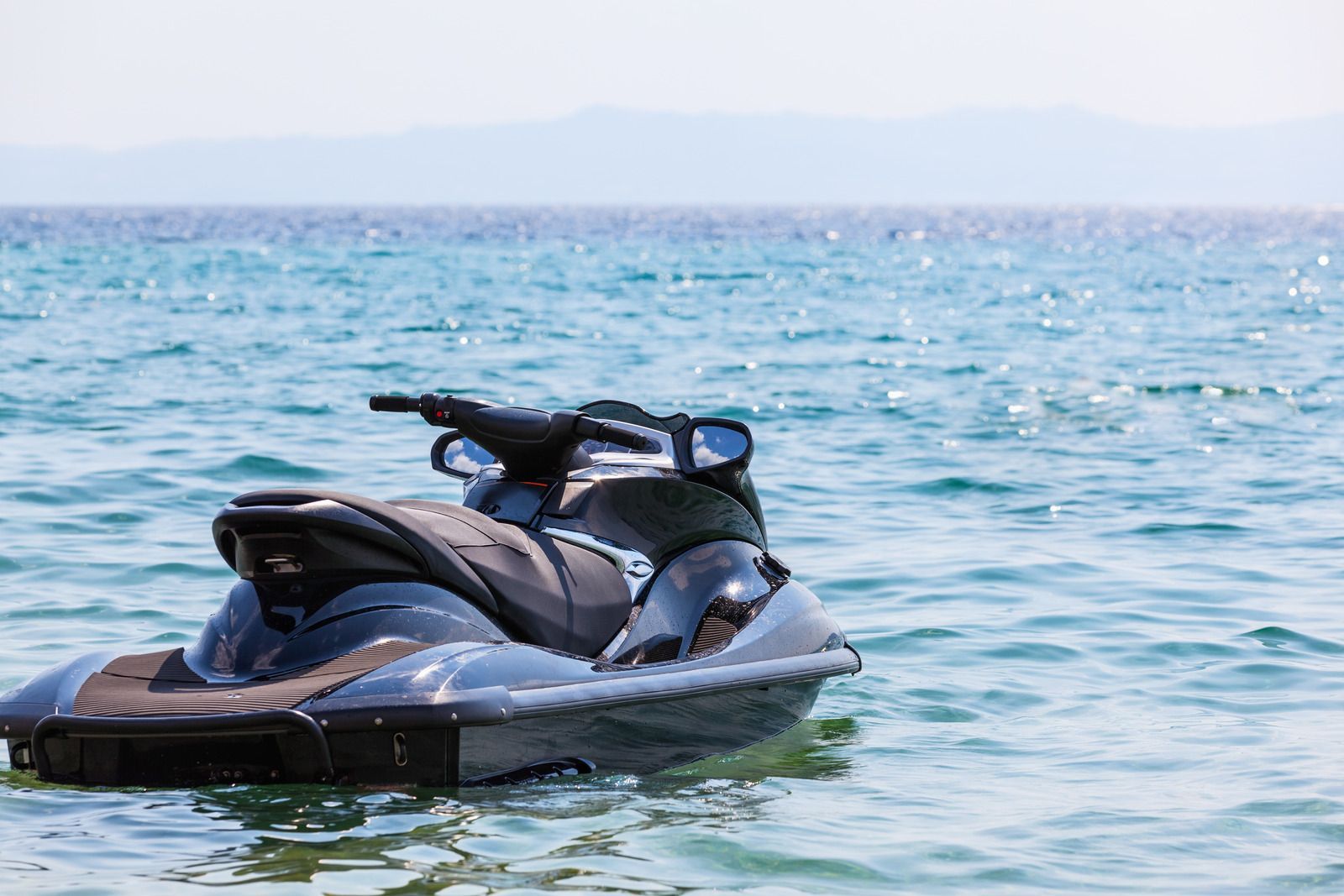 Jet ski floating on clear blue water; distant shoreline visible.