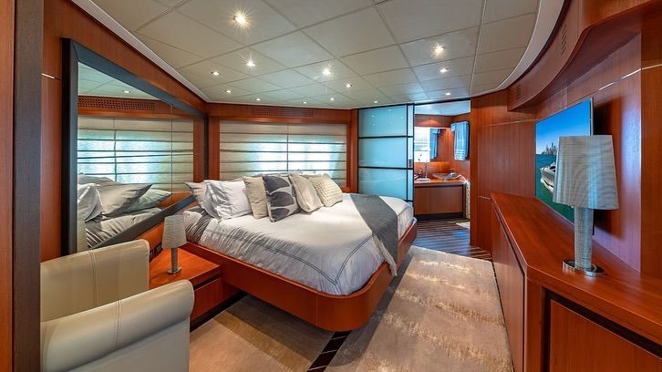 A bedroom on a yacht with a large bed and a television.